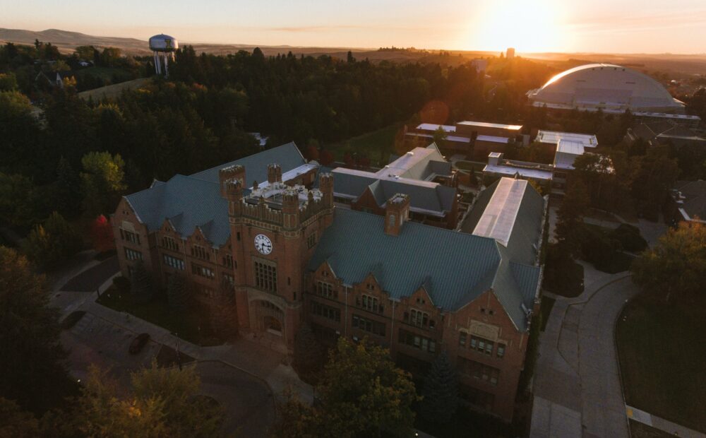 A bird's eye view shows the University of Idaho admin building and clock tower at sunset.