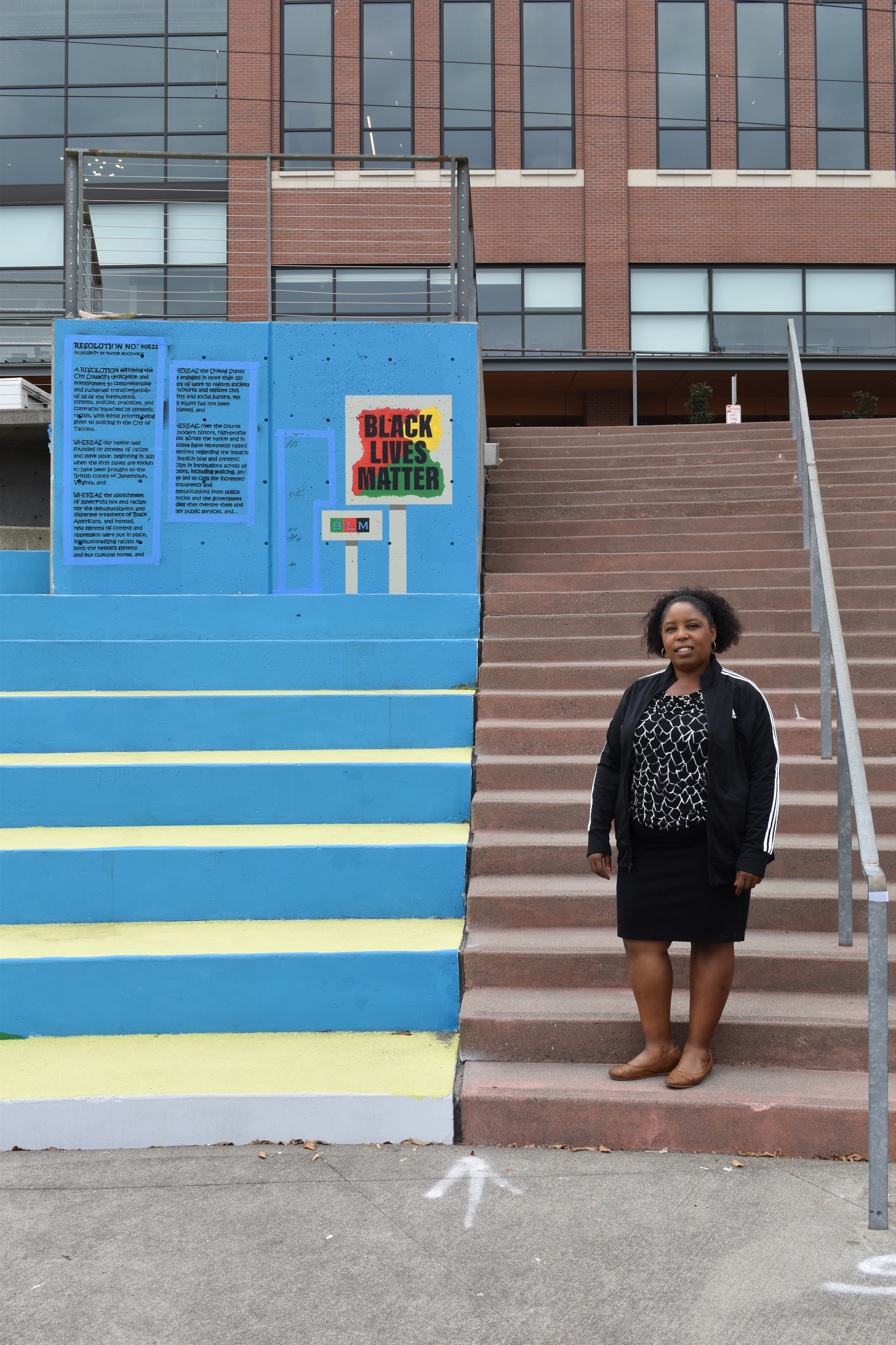 Lead-artist Dionne Bonner stands next to a portion of the mural, which shows the resolution by Tacoma's city council on their commitment to anti-racism. Photo by Lauren Gallup.