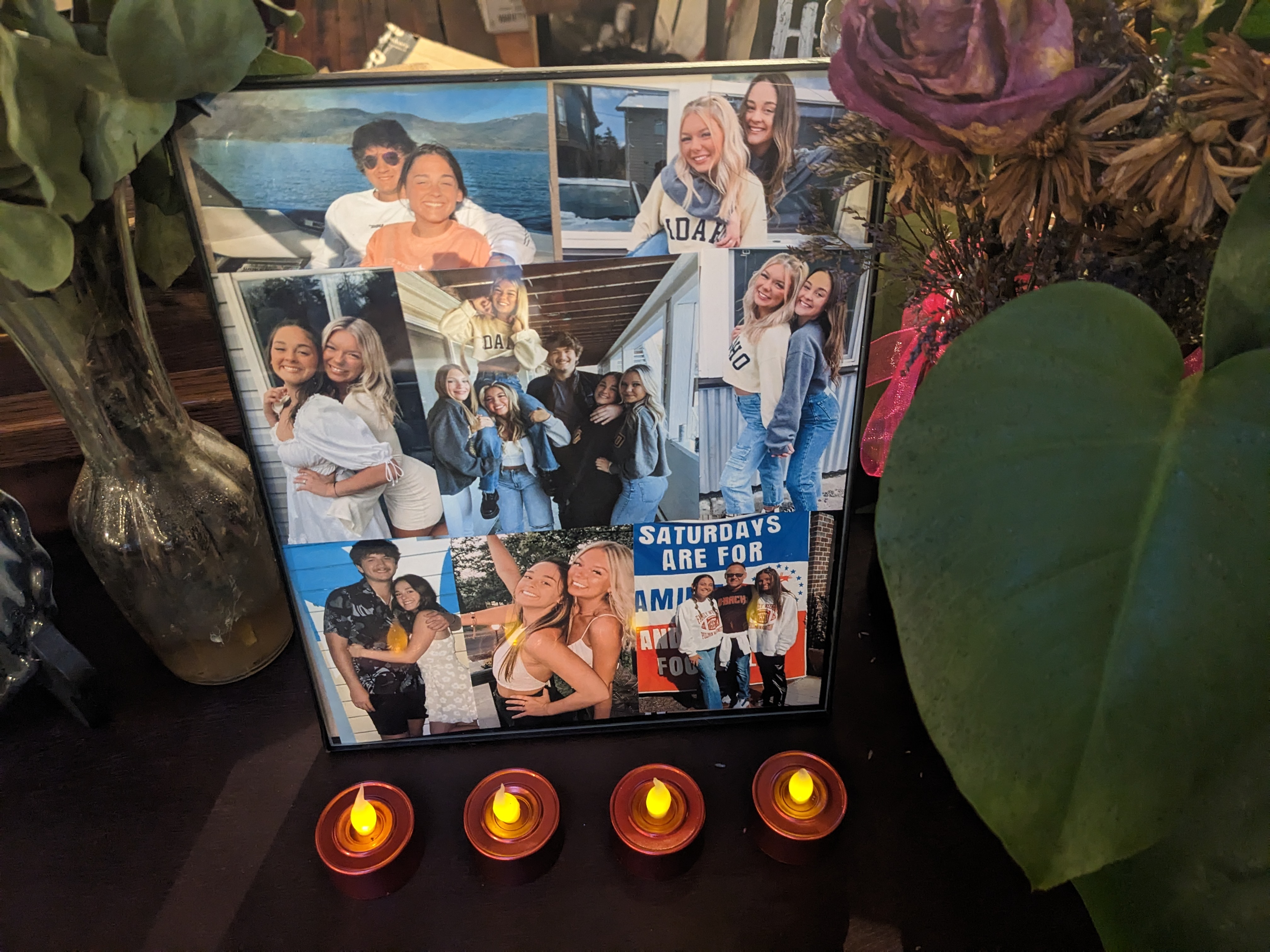 A poster shows a collage of photos of the four victims of the Moscow homicides. Four small candles sit before the poster on a dark brown table.