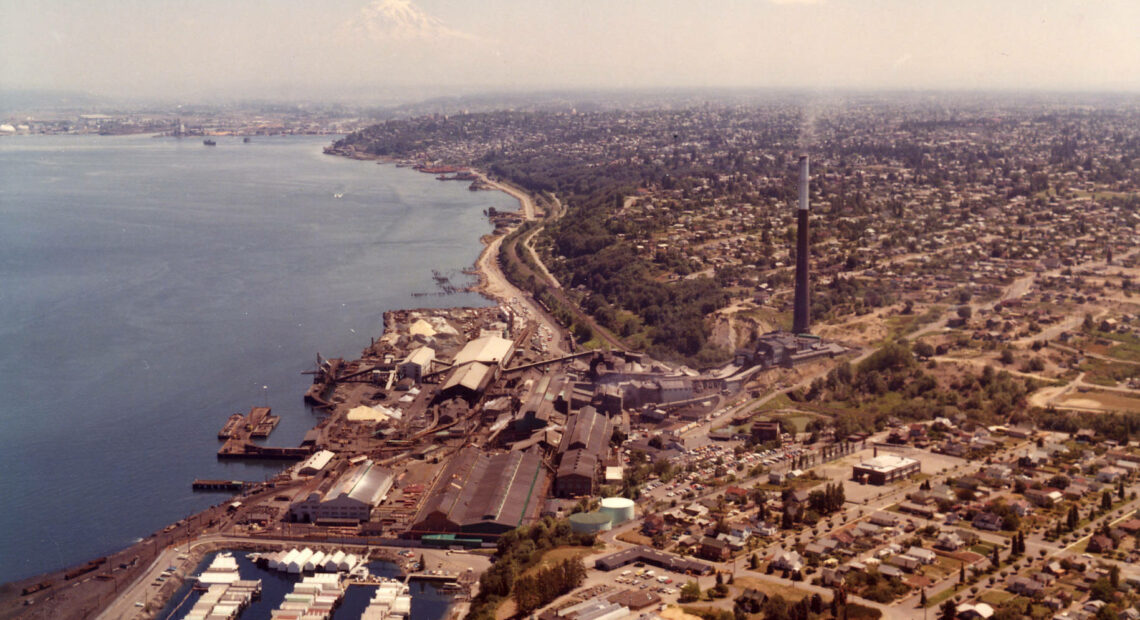 An image of the ASARCO smelter in Tacoma, showing the smokestack rising above the waterfront. Photo credit Tacoma Public Library.