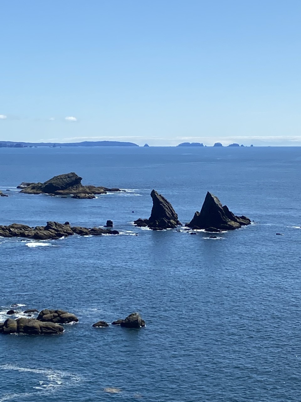 Blue water stretches to the horizon dotted with rocky peaks in the water.