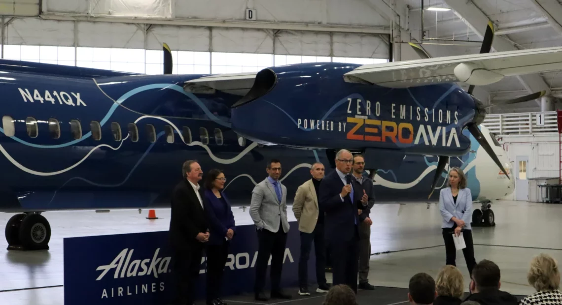 Tom Banse / NW News Network Elected officials and corporate leaders gathered in a Paine Field hangar to celebrate the handover of a retired Alaska Airlines Q400 turboprop, which will be converted to hydrogen-electric propulsion over the next year