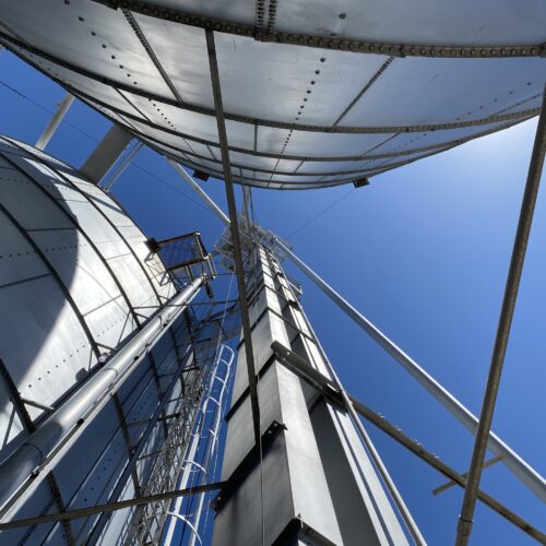 A mechanism that shuttles grain, called a leg, spires into the sky amid the bins at Northwest Grain Growers in Walla Walla. The leg carries grain dumped from trucks into receiving pits, up in buckets, sometimes well over 100 feet before the grain gets distributed to the many different grain bins and storage facilities (Credit: Anna King / Northwest News Network)