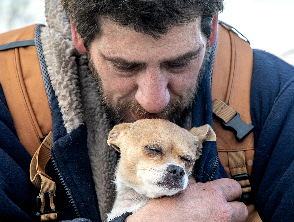 A man holds a dog close to his chest