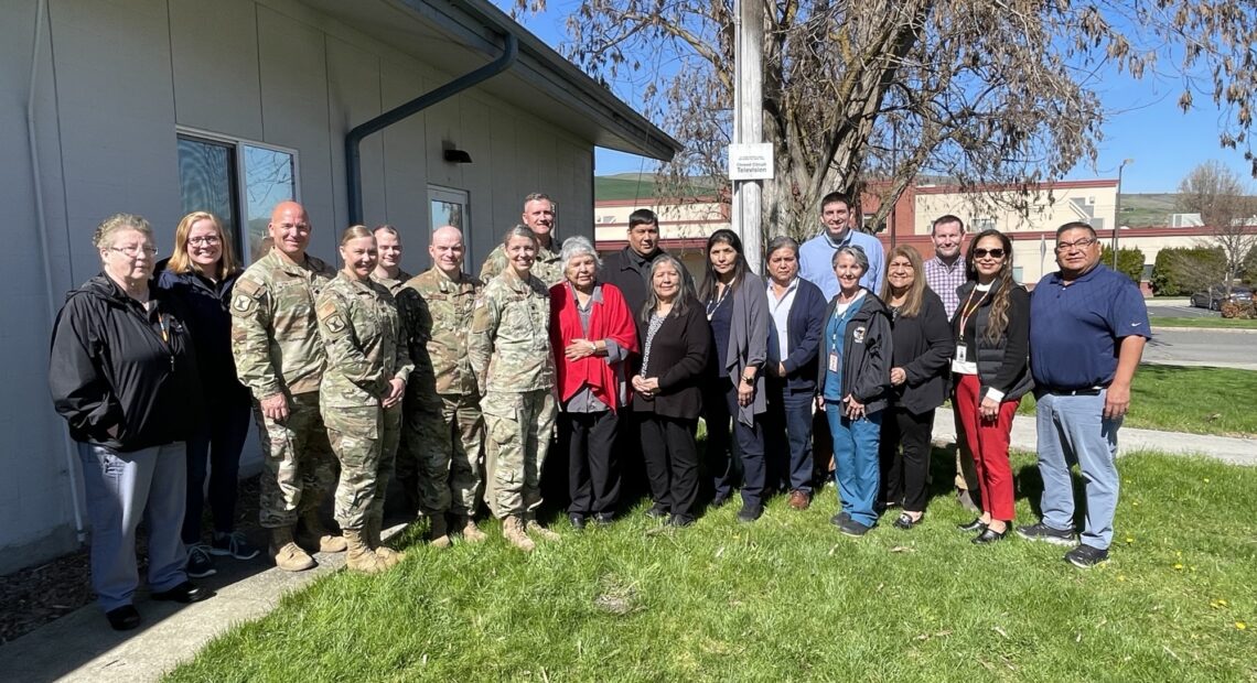 A group of health workers and National Guard members pose for a group photo outdoors.