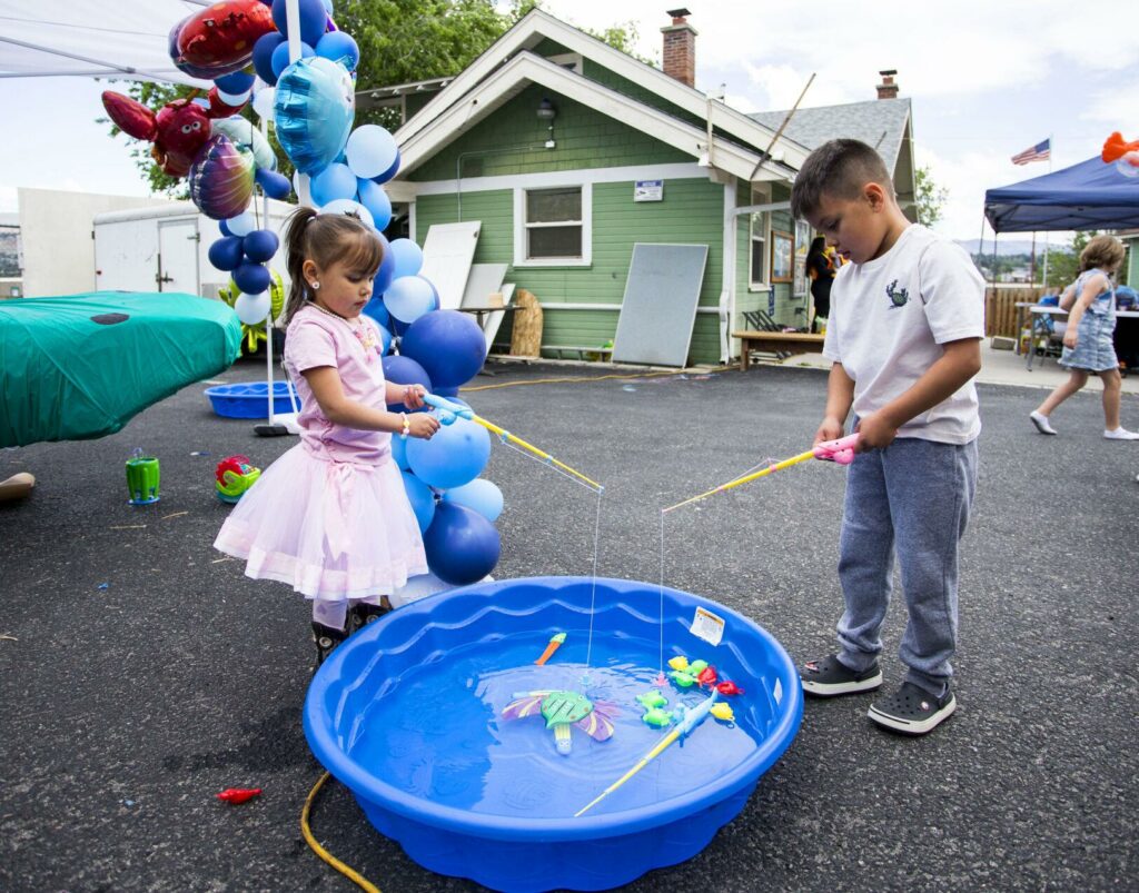 Jasibe Unda, 4, and her brother, Sebastian, 6, of Ephrata, fish while at CAFÉ's Pachanga & Mercadito resource fair. (Credit: Loren Benoit / Wenatchee World)