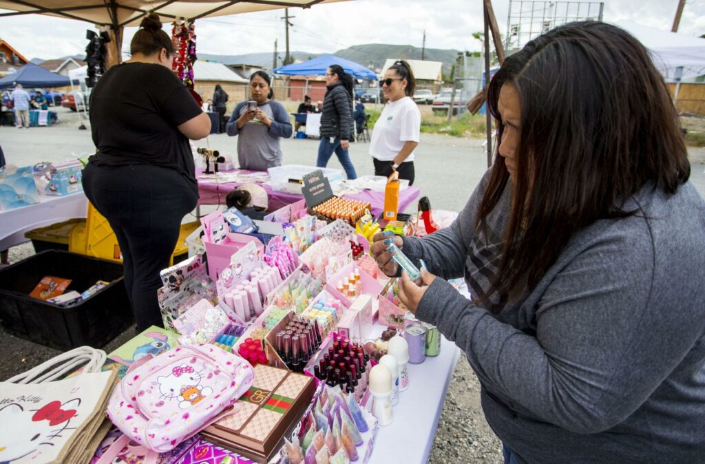 Elizabeth Jimenez browses nail polish at Ariana Hernadez's booth while at CAFÉ's Pachanga & Mercadito resource fair in Wenatchee. (Credit: Loren Benoit / Wenatchee World)