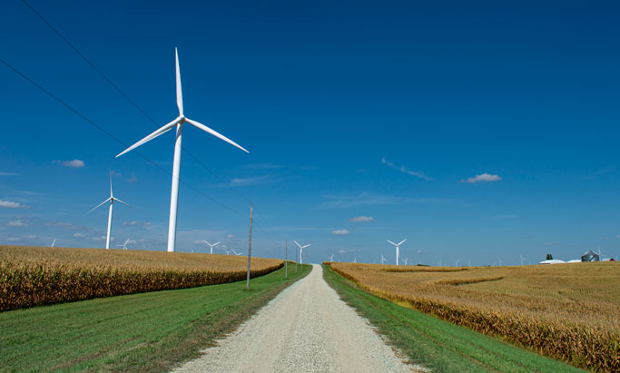 Wind turbines along a rural road. Washington will have to develop renewable energy projects to meet its carbon-free goals. A lot of that development will likely happen in rural areas. (Credit: Roy Harryman, Flickr Creative Commons)