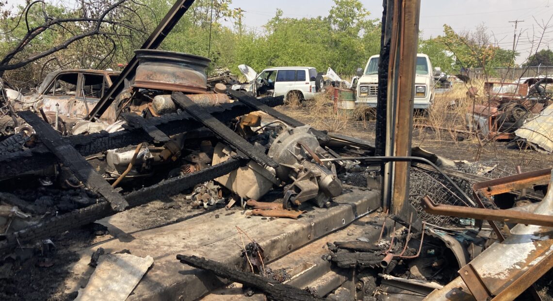 An industrial lot in Walla Walla with burned wood and vehicles.