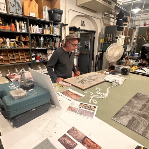 David Miller stands over his work table in the basement of the Whatcom Museum. Here he works on items for the exhibits upstairs, as well as his work as a scientific illustrator. (Credit: Lauren Gallup / NWPB)