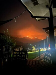 A night photo shows an orange fire blazing in the distance from the Rivaura Tasting Room Patio.