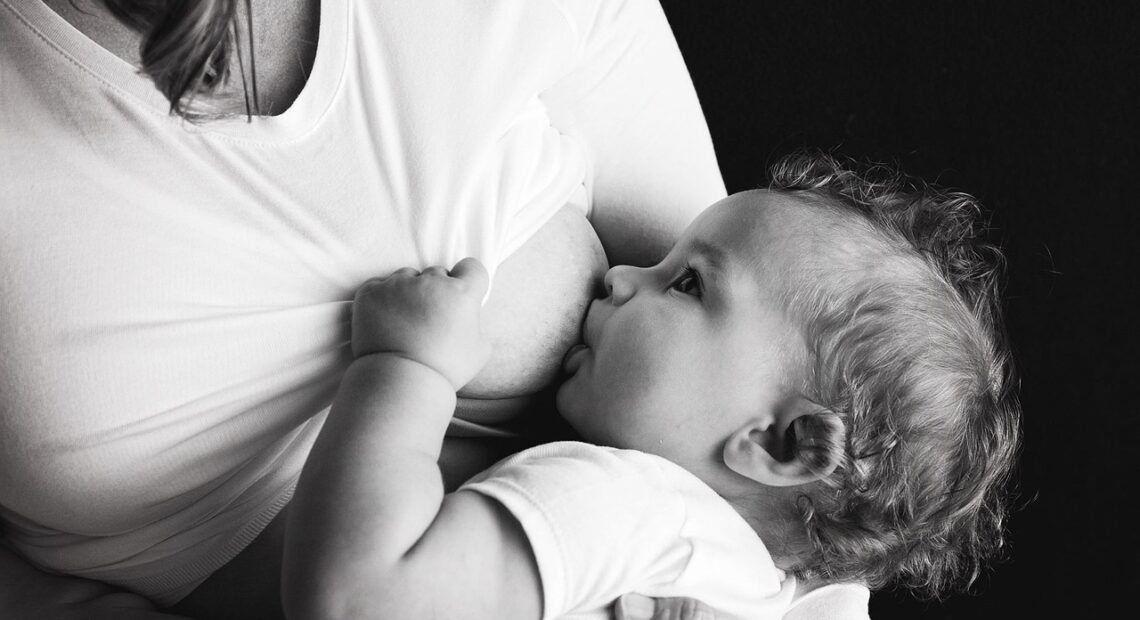 A black-and-white image of an infant being breastfed.