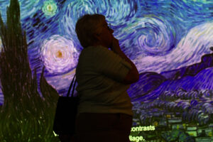 A visitor looks at artwork by Vincent Van Gogh at "Van Gogh: The Immersive Experience." (Credit: Rachel Sun / NWPB)