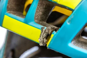 An up close photo of a turquoise bike helmet. Part of the helmet has a crack in it.