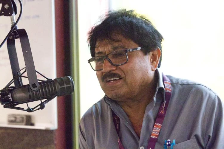 A man stands at a microphone at a radio station.