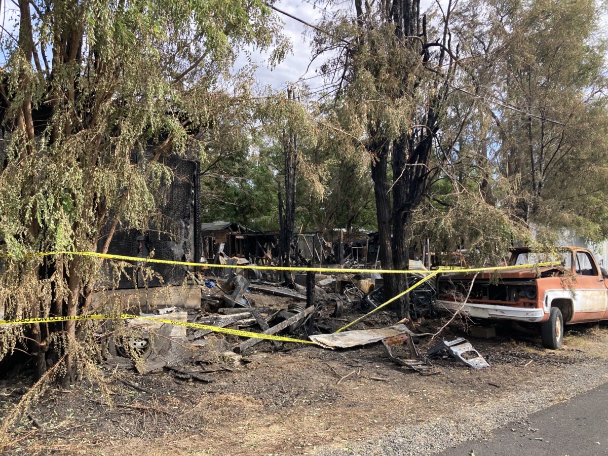 A burnt junkyard with a truck and fire tape