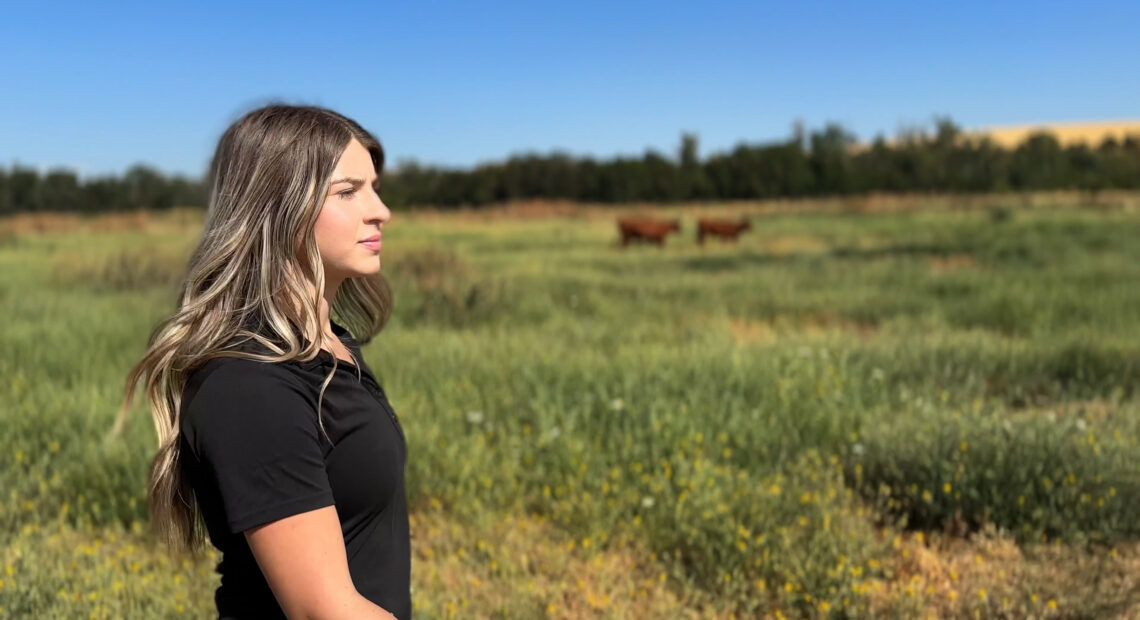 WWCC ag student stands in a field with cattle in the background