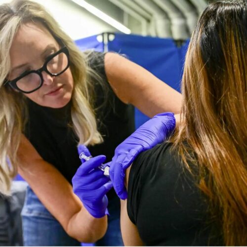 A woman administers a vaccine to another person.