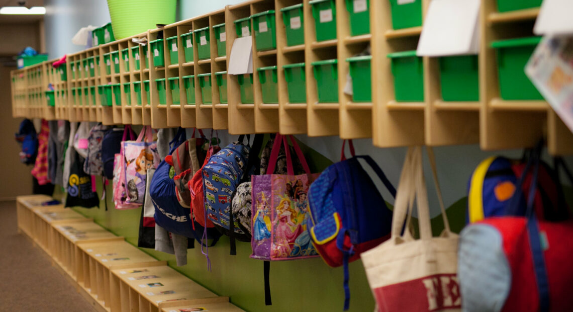 Colorful backpacks hang in cubbies.