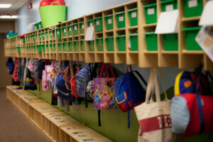 Colorful backpacks hang in cubbies.