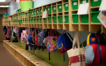 Colorful backpacks hang in cubbies.