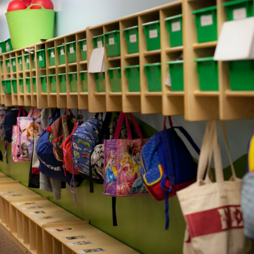 Colorful backpacks hang in cubbies.